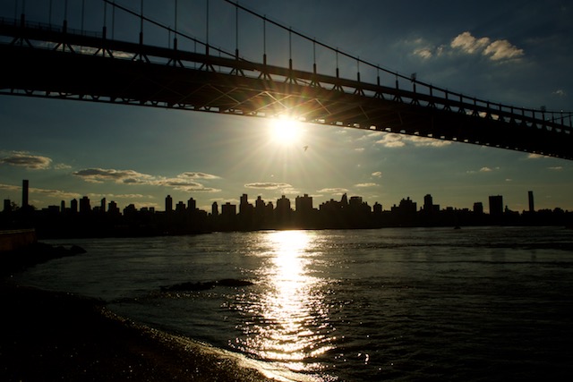 View of sun setting behind the NYC skyline, the East River and the Robert F. Kennedy Triborough Bridge from Astoria Park