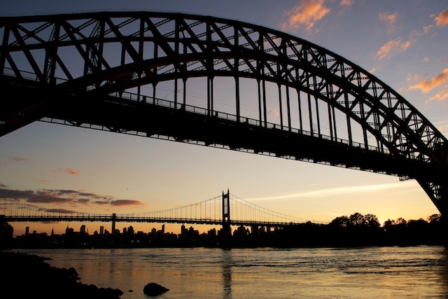 View of sun setting behind the NYC skyline, the East River and the Robert F. Kennedy Triborough Bridge from Astoria Park