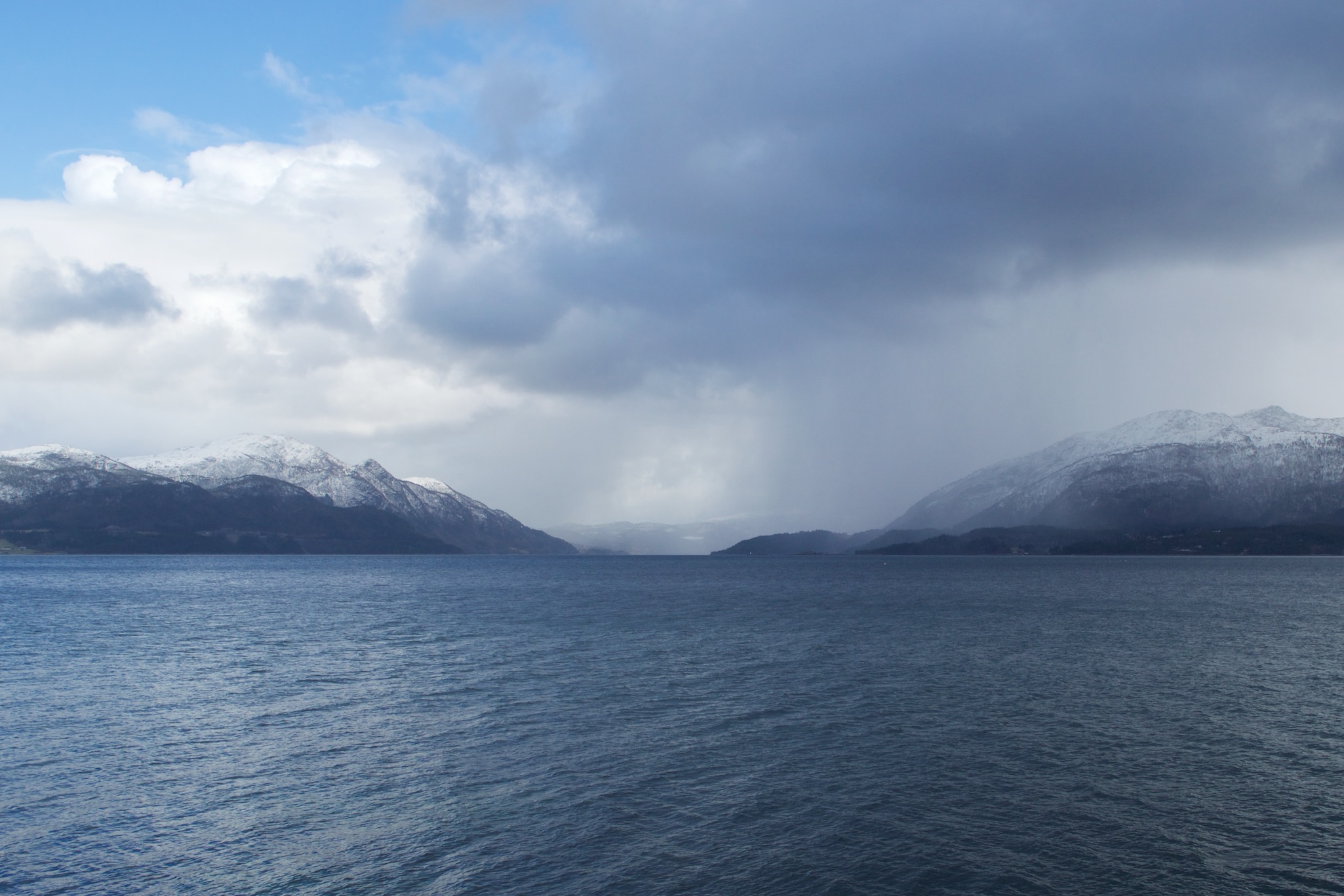 View of blue sky, blue water, and mountains over the fjord in More Og Romsdal, Norway